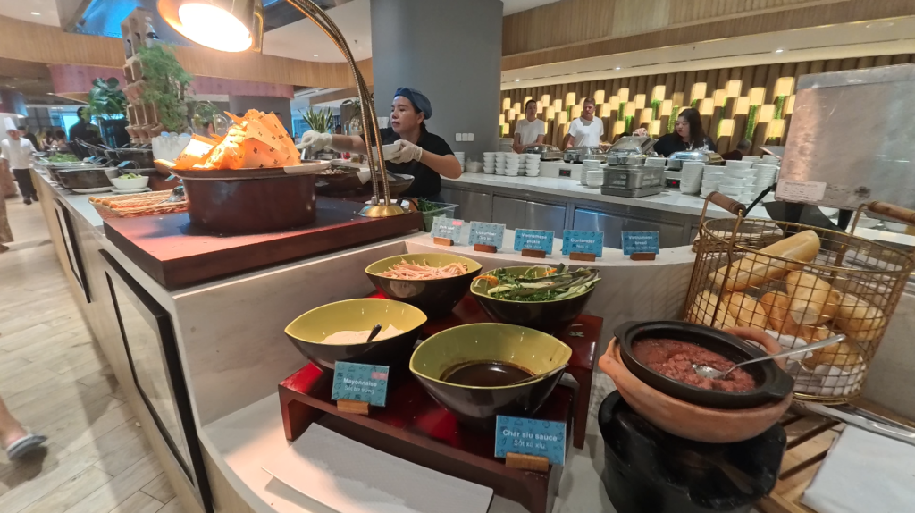 現做越式河粉區： 「早餐自助區現煮越式河粉檯，配料豐富，廚師忙碌備餐中」